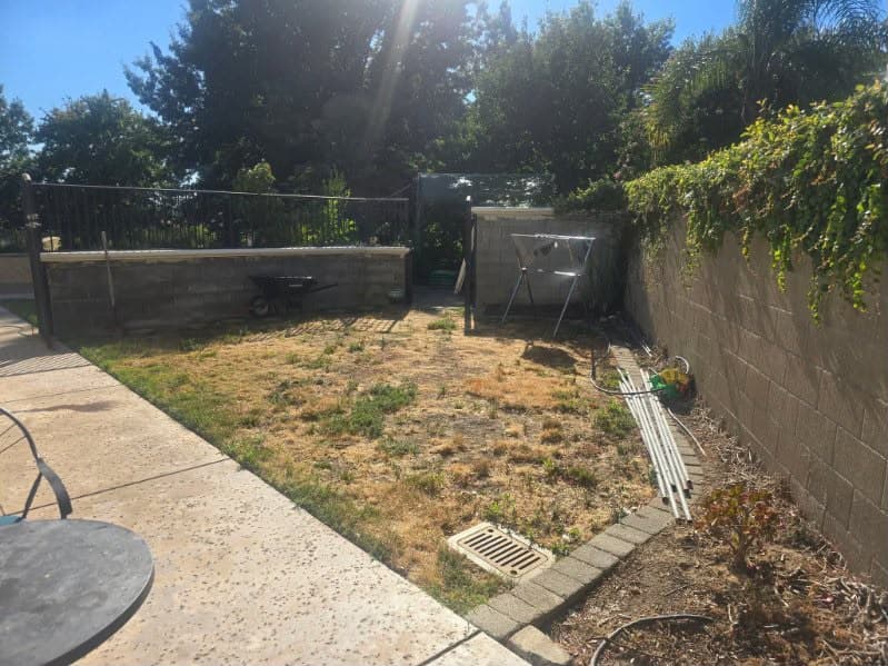 Backyard before paver patio installation with bare dirt and dead grass in Sacramento CA