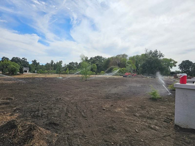 Large lawn area before sod with new sprinkler irrigation system running in Sacramento CA